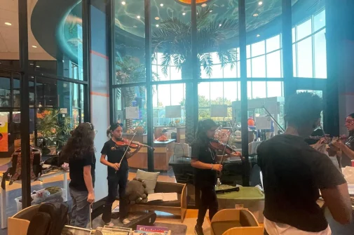 Alumnos del Programa de orquesta infantil y juvenil The Nucleus Orchestral Texas tocando violin en el Imagine Early Education & Childcare Fall Festivall